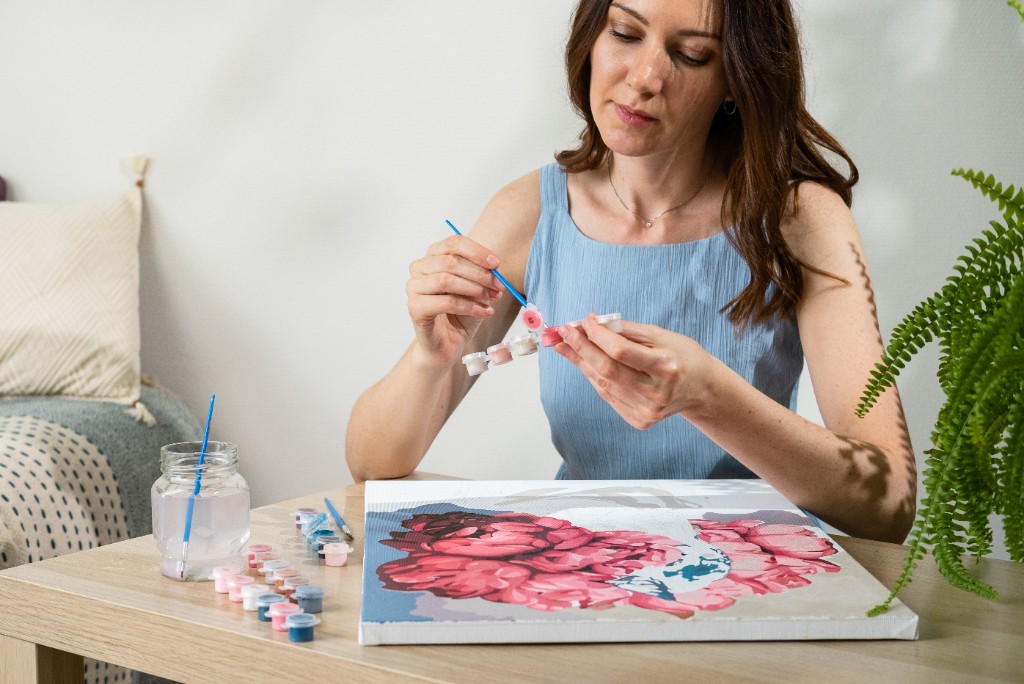 Woman painting a custom paint by number floral kit at home